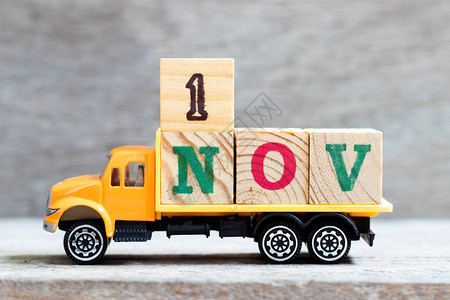 卡车在木材背景上持有1nov字的母块图片