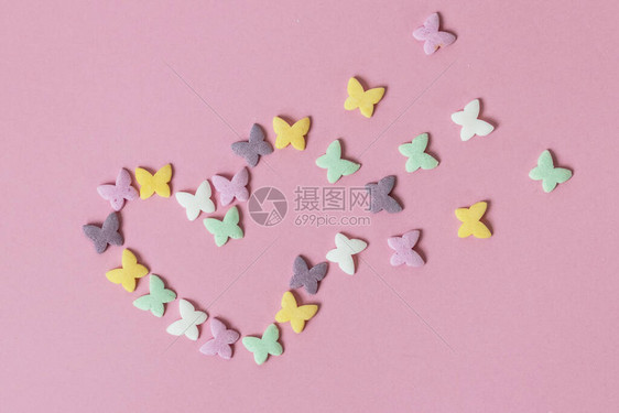 多色糕点多色薄粉喷洒和滴虫以粉红色背景的衰变心脏的形式呈现出来图片