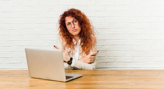 与笔记本电脑接头的女红发姑娘正试图在两种选择中作出选择图片