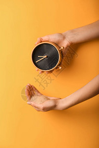 彩色背景上带时钟和沙子的女手时间管理概念图片
