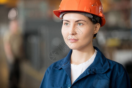 身穿蓝色工作服和防护头盔的年轻漂亮女工程师图片