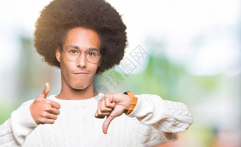 身着ffro头发的年轻非洲美国人戴着眼镜举起拇指持不同意见和协议表达方式图片