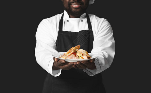 深色背景中提供美味佳肴的非洲裔美国男厨师图片