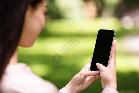 韩国妇女使用智能手机露户黑屏空白模拟肩对面和广告复制空背景