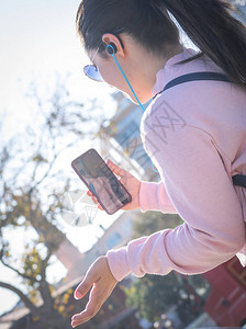 穿着粉红色毛衣的年轻女孩在智能手机上的实时聊天中表现得很出色图片