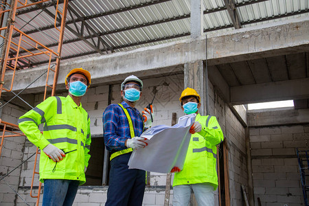 亚洲工程技术人员团队介绍和监督工人在工地建房图片