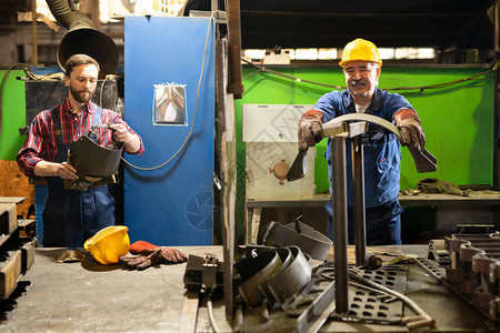 两位当代机器制造商之一准备金属工件进行加工图片