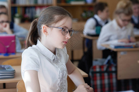 十几岁的女孩学生在教室的课桌前戴着眼镜图片
