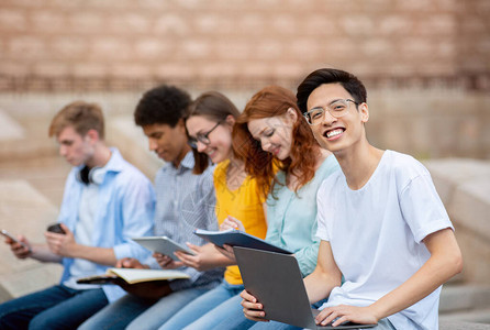 亚洲学生与坐在大学楼外的同学一起学习学生活理念图片