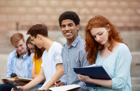 多文化学生坐在大学楼外学习准备考试国外高等教育图片