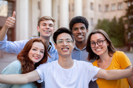 快乐的多元文化学生在户外大学楼附近合影自拍图片素材