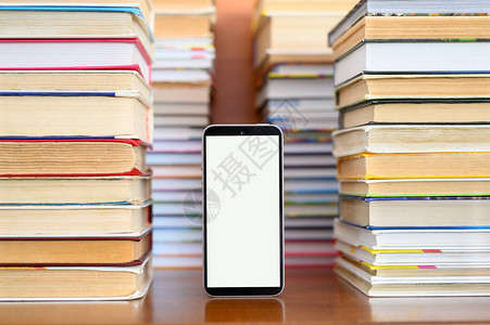 一部带有空白显示屏的智能手机站在高大的旧书堆旁边用电子书代图片