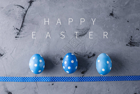 三个明亮的蓝色圆点鸡蛋和灰色背景的丝带图片