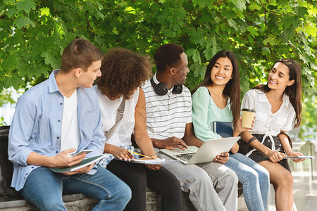 快乐的大学生坐在大学校园的长椅上准备考试或课间休息图片