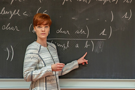 微笑的女老师大学里的年轻女教师大学课堂教学黑板上用粉笔描述数据图片
