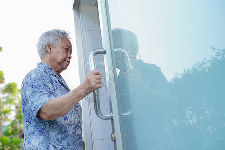 亚洲老年妇女病人在护理医院病房用手打开厕所浴室图片