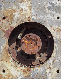 在阳光和阴影的中心用螺栓和圆形驱动轴在钢板上用圆孔关闭旧生锈机械图片