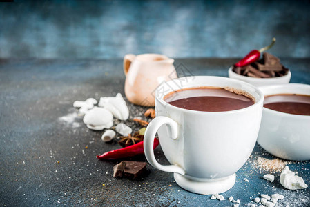 热巧克力杯巧克力碎片糖棉花糖红辣椒和香料深蓝色混凝土背图片