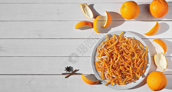 糖渍橙皮是儿童和成人最喜欢的款待自制蜜饯橙皮和橙子在白色木桌上的图像顶视图片