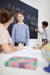 小学生站着回答老师在课堂上数学课时问他的问题图片