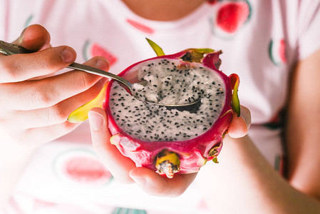 一个女人用铁勺吃着热带水果火龙果图片