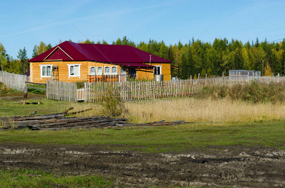 一座用木头制成的红屋顶新私人住宅矗立在一条肮脏的道路附近图片