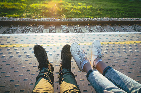 夏日落时女孩和男孩双腿在火车平台图片