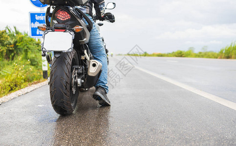特写摩托车轻便摩托车在雨中在湿滑的道路上穿过水坑图片