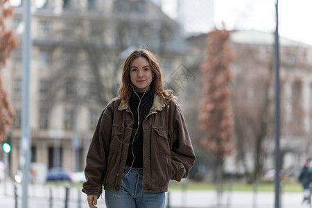 带着真诚笑容的年轻女子在城市里听耳图片