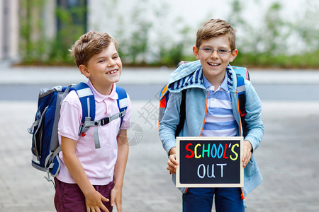 上学路上的小学生健康的孩子兄弟和最好的朋友在街上离开家学校在粉笔
