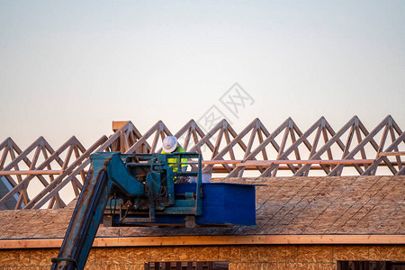 建筑工人或屋顶工人在工作时使用机械臂在新建房图片