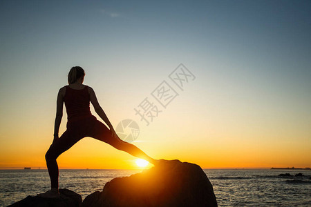 日落时在海滩上练习瑜伽的女人的剪影图片