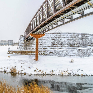 方形框架湖和建筑物在冬天多云的天空下被雪地包围一条环形通道向横跨图片