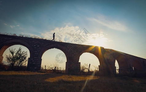 一个男人走在砖结构桥上太阳照耀图片
