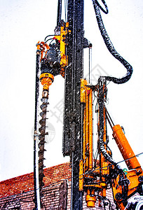 打桩设备的钻机基础和基础飘落的雪花背景上的图像模糊在北方工作艰图片