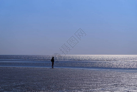 海滩上单身人类向地平线看的休眠之光图片
