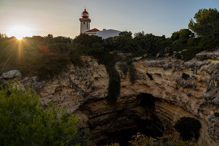 在葡萄牙Algarve地区日落时被树木阳光和海洞穴所包围的Alfan图片