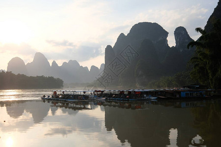 广西阳朔桂林市丽江漓江的明亮日出山和森林有雾的剪影水上旅游船山在河里的倒影图片