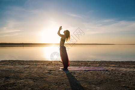 日落时在沙滩上做瑜伽的月光女人图片