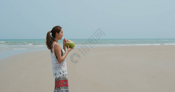 女人在海滩喝椰子图片