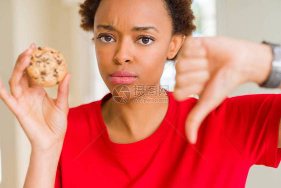 年轻非裔美国女人吃巧克力薯片饼干时脸色愤怒图片