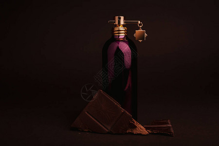 棕色背景中的一瓶香水和巧克力图片