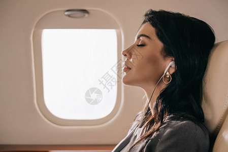 在私人喷气式飞机上闭眼听音乐的有吸引力的商业图片
