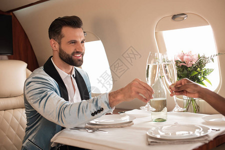 美籍非洲女在私人飞机的餐桌上与优雅男子握着香图片
