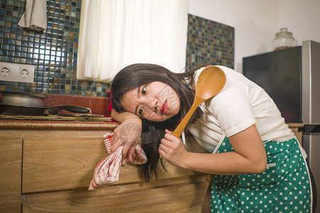 年轻疲惫和压力大的亚洲韩国女身穿厨师围裙工作靠在厨房水槽上的家务生活图片