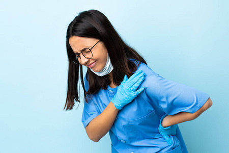 身处孤立的蓝色背景的外科妇女因努力而肩膀疼痛图片
