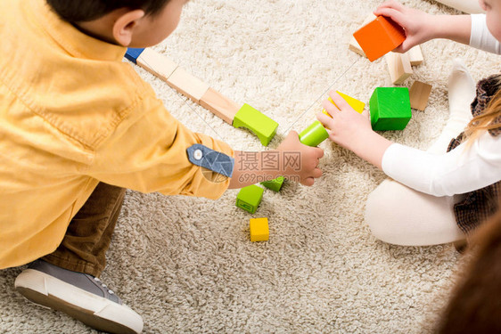 孩子们在地毯上玩彩色木块的剪影图片