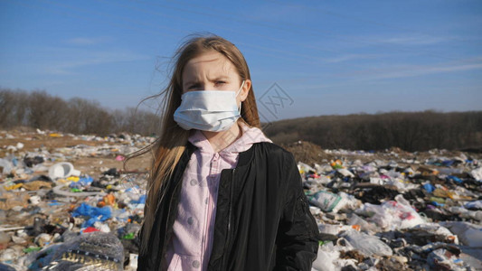 以医疗保护面罩为掩护的女童在肮脏垃圾堆场的背景之下图片