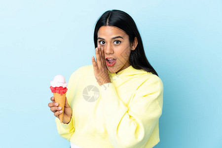 年轻哥伦比亚女人带着一个玉米角冰淇淋孤立在蓝背景的蓝色背景下悄图片
