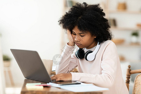 在网上课堂从家中学习时坐在笔记本电脑上睡觉的非洲沉睡女学生图片